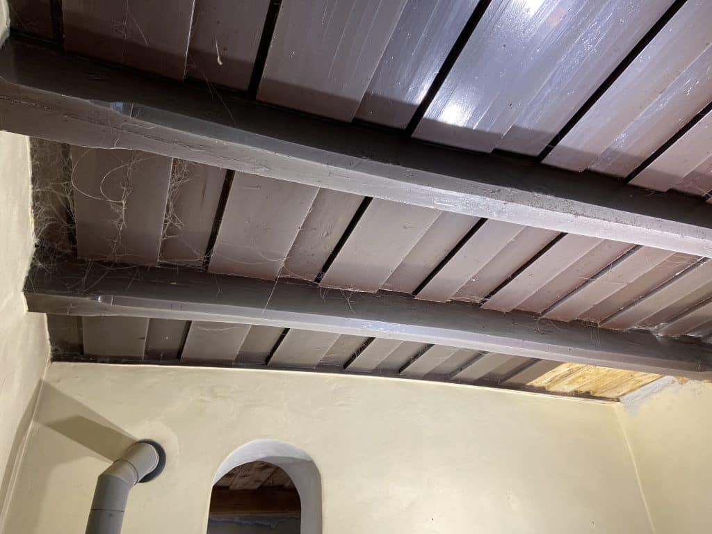 Drevený strop v interiéri so starým náterom.